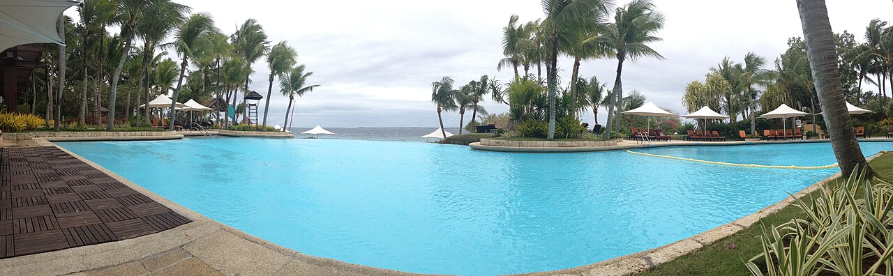 Palm-lined infinity pool at Shangri-La Mactan overlooking the sea.